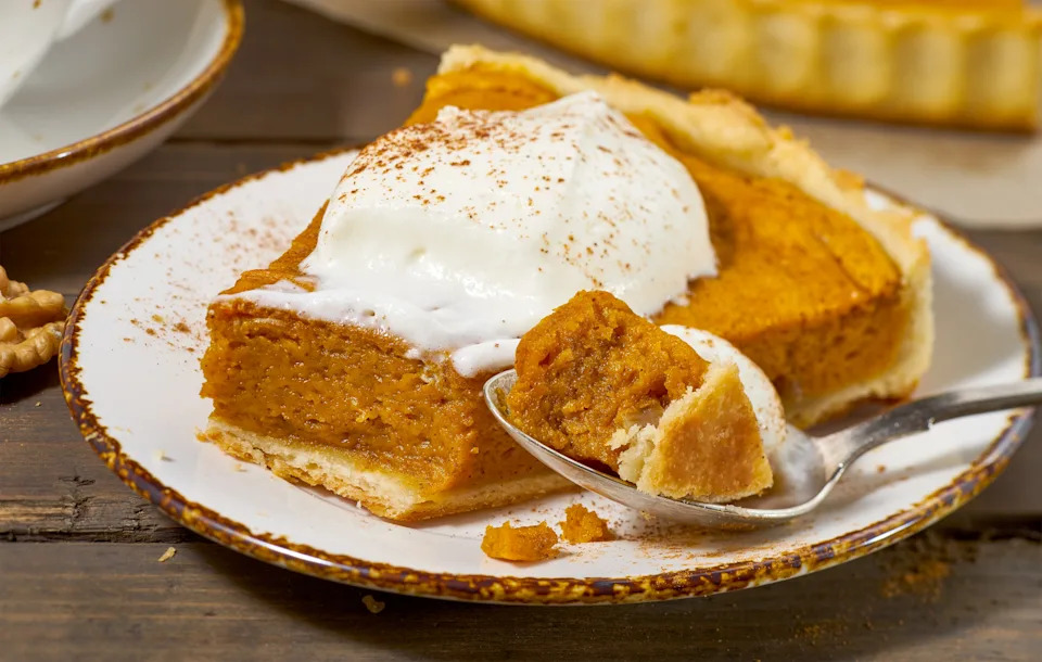 Slice of pumpkin pie with whipped cream on a plate