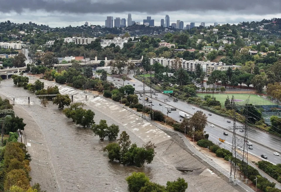 An aerial view of water flowing in the Los Angeles River, swollen by storm runoff, with the downtown LA skyline beyond on October 14, 2025 in Los Angeles, California. (Getty Images)