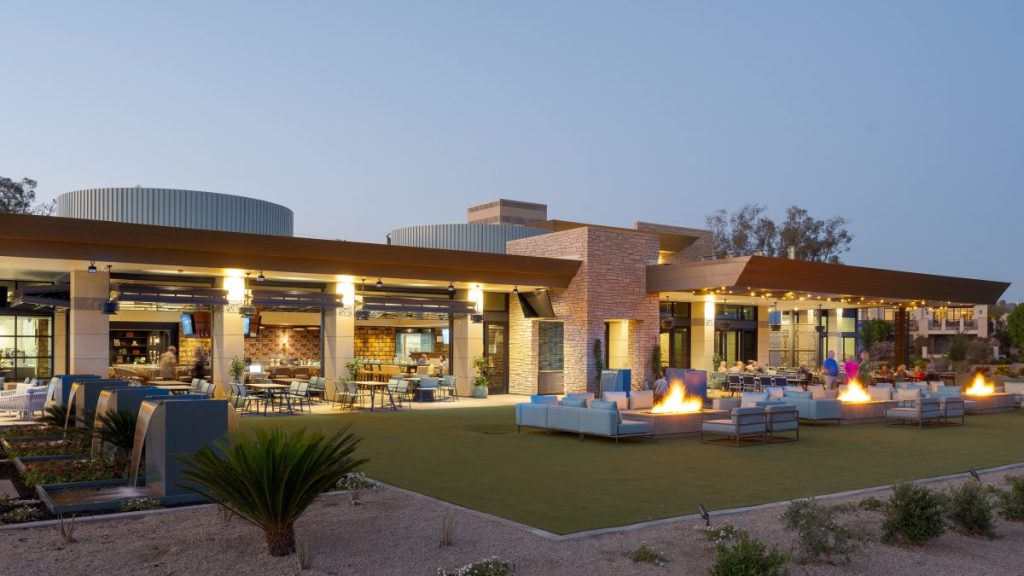 A golf club patio at dusk, with lounge seating and fire pits.