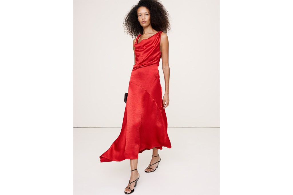 A woman in a red satin dress with a cowl neck and black heels.