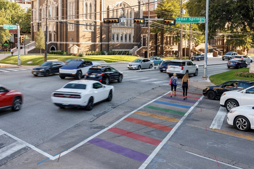 Cars drive past a rainbow crosswalk at the intersection of Cedar Springs Road and Oak Lawn...