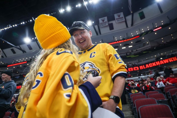 Savannah Suchy, 10, of Fort Atkinson, Wisconsin looks at her dad Michael Suchy after Nashville Predators right wing Luke Evangelista grave her a puck before a game against the Blackhawks, Nov. 28, 2025, at the United Center. (Dominic Di Palermo/Chicago Tribune)