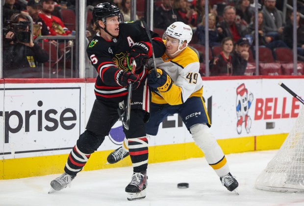 Blackhawks defenseman Connor Murphy (5) passes the puck while getting checked by Nashville Predators left wing Reid Schaefer (49) during the second period, Nov. 28, 2025, at the United Center. (Dominic Di Palermo/Chicago Tribune)