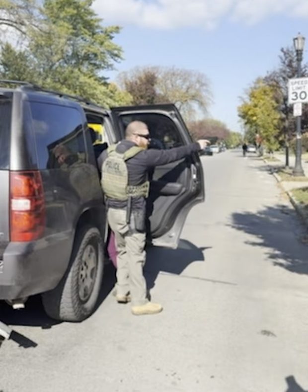 After a car accident in Evanston, a federal immigration agent points a weapon at least twice toward onlookers while attempting to restrain a woman in Evanston on Oct. 31, 2025. (Lindsey Rose)