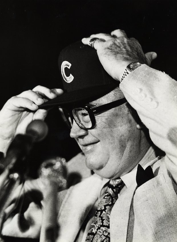Harry Caray puts on a Chicago Cubs hat at a press conference on Nov. 16, 1981, after he signed a two-year contract to broadcast Cubs games. (Walter Kale/Chicago Tribune)