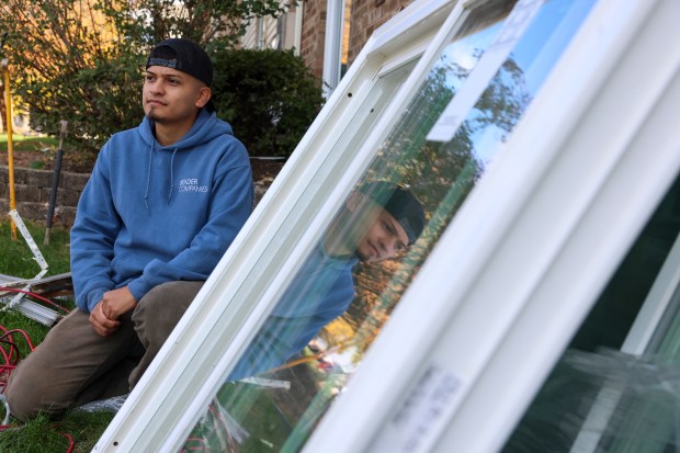 Efrain Cuevas, 24, stands among window replacement supplies strewn outside of Hoffman Hills Apartments after federal agents raided the complex and detained three window installers on Oct. 31, 2025, in Hoffman Estates. (Stacey Wescott/Chicago Tribune)