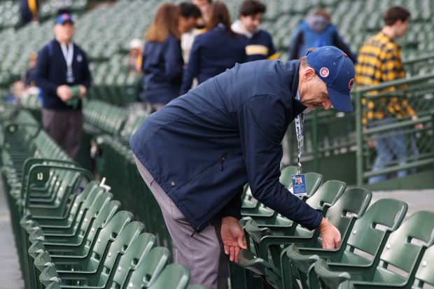 A guest services worker wipes off moisture from seats before a Northwestern-Michigan football game at Wrigley Field on Nov. 15, 2025, in Chicago. (John J. Kim/Chicago Tribune)