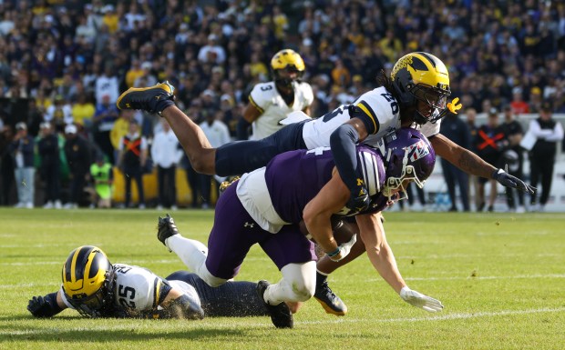 Northwestern tight end Hunter Welcing is tackled by Michigan defensive back Jyaire Hill (20) after a first-down reception in the second quarter at Wrigley Field on Nov. 15, 2025, in Chicago. (John J. Kim/Chicago Tribune)