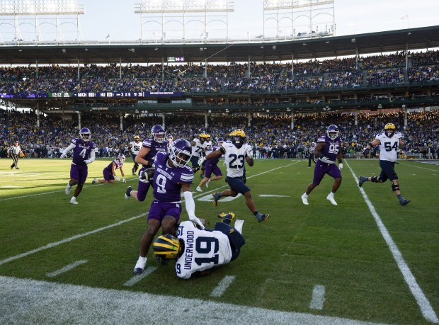 Michigan quarterback Bryce Underwood (19) tackles Northwestern defensive back Braden Turner (9) after an interception by Turner in the fourth quarter at Wrigley Field on Nov. 15, 2025, in Chicago. (John J. Kim/Chicago Tribune)