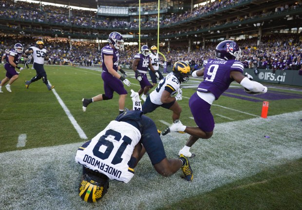 Michigan quarterback Bryce Underwood (19) tumbles after tackling Northwestern defensive back Braden Turner (9) following an interception by Turner in the fourth quarter at Wrigley Field on Nov. 15, 2025, in Chicago. (John J. Kim/Chicago Tribune)