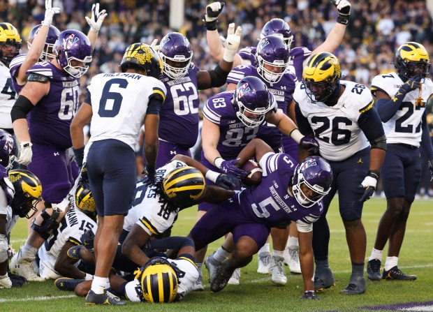 Northwestern running back Caleb Komolafe (5) rises after crossing the end zone for a touchdown against Michigan in the fourth quarter at Wrigley Field on Nov. 15, 2025, in Chicago. (John J. Kim/Chicago Tribune)