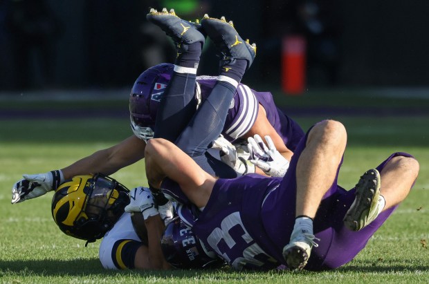 Michigan running back Bryson Kuzdzal, left, is tackled by Northwestern defenders in the fourth quarter at Wrigley Field on Nov. 15, 2025, in Chicago. (John J. Kim/Chicago Tribune)