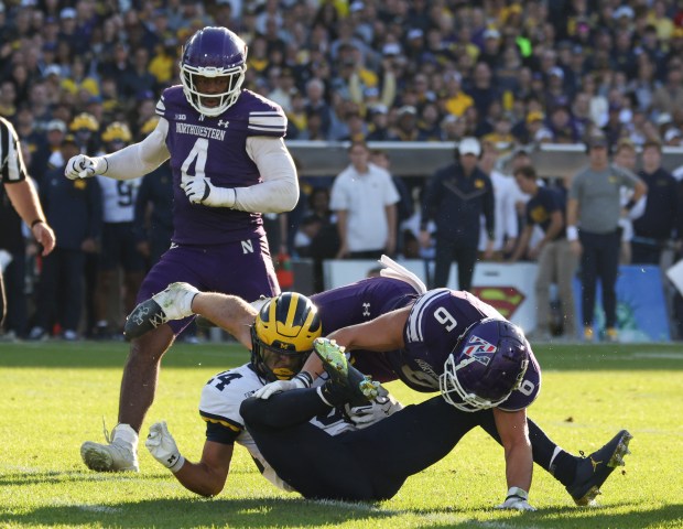 Michigan running back Bryson Kuzdzal (24) is tackled by Northwestern defensive back Robert Fitzgerald (6) in the fourth quarter at Wrigley Field on Nov. 15, 2025, in Chicago. (John J. Kim/Chicago Tribune)