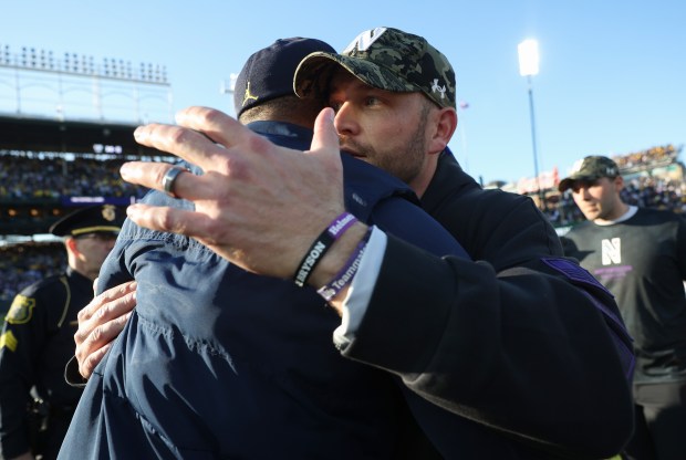 Northwestern head coach David Braun, right, congratulates Michigan head coach Sherrone Moore on a 24-22 Michigan win at Wrigley Field on Nov. 15, 2025, in Chicago. (John J. Kim/Chicago Tribune)