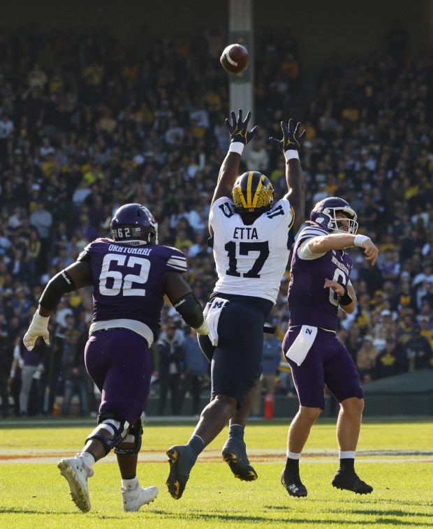 Northwestern quarterback Preston Stone (8) throws the ball away as Michigan defensive lineman Enow Etta (17) closes in in the third quarter at Wrigley Field on Nov. 15, 2025, in Chicago. (John J. Kim/Chicago Tribune)