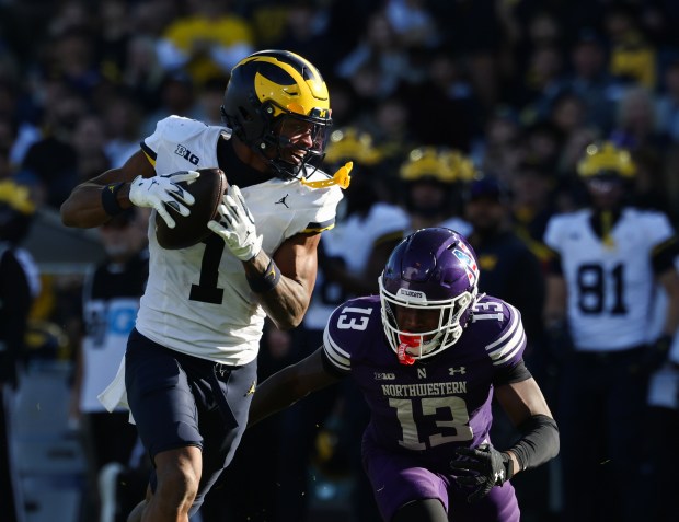 Michigan wide receiver Donaven McCulley (1) runs after a catch as Northwestern defensive back Josh Fussell (13) chases in the third quarter at Wrigley Field on Nov. 15, 2025, in Chicago. (John J. Kim/Chicago Tribune)