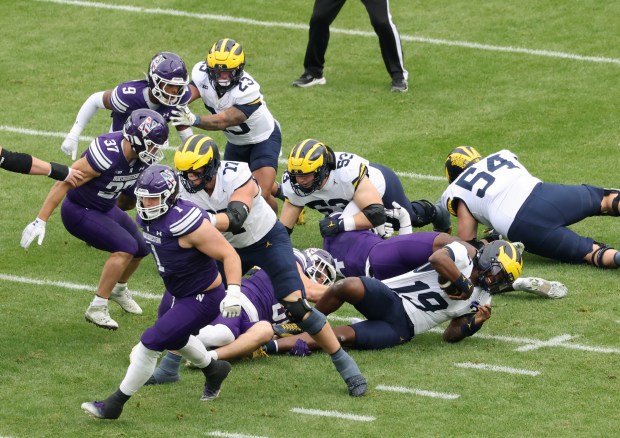 Michigan quarterback Bryce Underwood (19) is tackled by Northwestern defensive lineman Aidan Hubbard (91) in the first quarter at Wrigley Field on Nov. 15, 2025, in Chicago. (John J. Kim/Chicago Tribune)