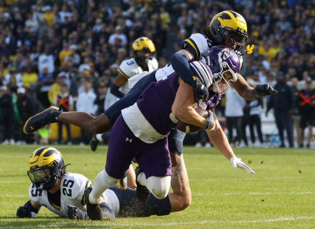 Northwestern tight end Hunter Welcing is tackled by Michigan defensive back Jyaire Hill (20) after a first-down reception in the second quarter at Wrigley Field on Nov. 15, 2025, in Chicago. (John J. Kim/Chicago Tribune)