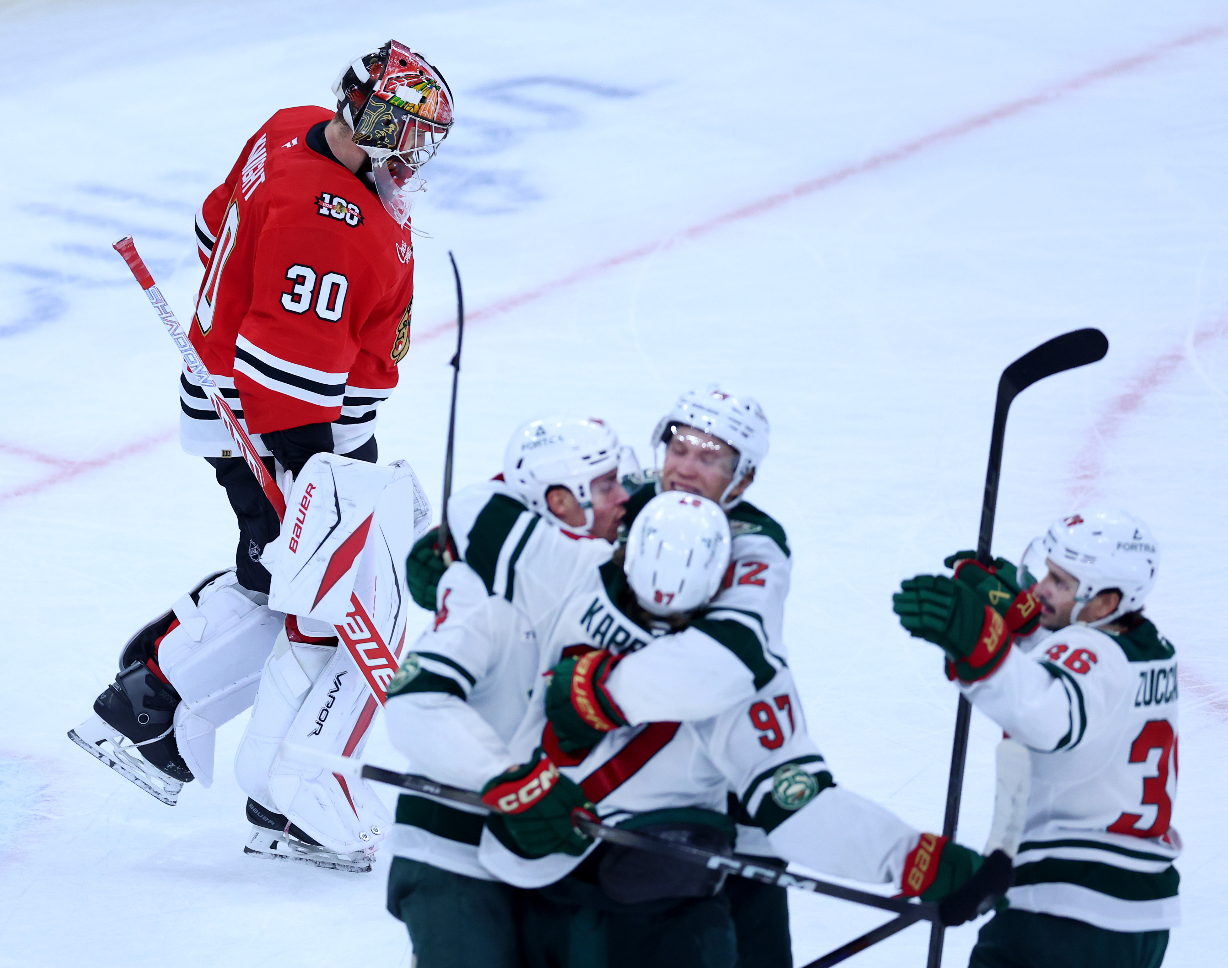Chicago Blackhawks goaltender Spencer Knight (30) skates off the ice as Minnesota Wild left wing Kirill Kaprizov (97) celebrates with his teammates after scoring the winning goal in overtime of a game at the United Center in Chicago on Nov. 26, 2025. (Chris Sweda/Chicago Tribune)