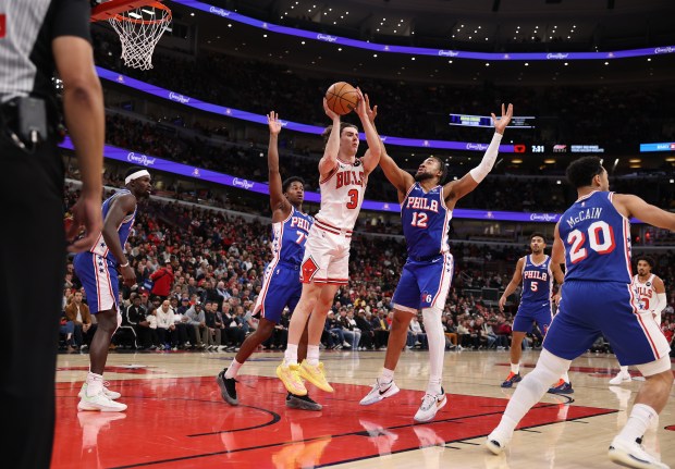 Chicago Bulls guard Josh Giddey (3) passes out while being pressured by Philadelphia 76ers guard Vj Edgecombe (77) and guard/forward Trendon Watford (12) in the first half of a game at the United Center in Chicago on Nov. 4, 2025. (Chris Sweda/Chicago Tribune)