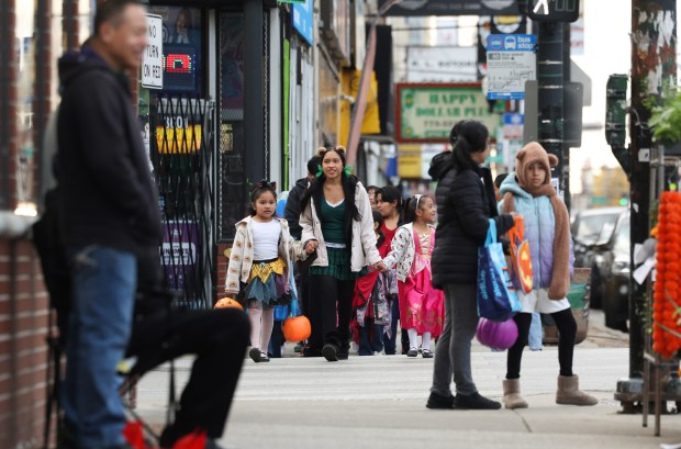 Trick-or-treaters walk on West 26th Street in the Little Village neighborhood of Chicago on Halloween, Oct. 31, 2025. (John J. Kim/Chicago Tribune)