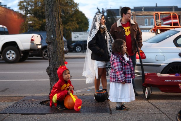 A young trick-or-treater chomps on candy while taking a break with her family on West 26th Street in the Little Village neighborhood on Chicago. (John J. Kim/Chicago Tribune)