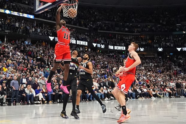 Chicago Bulls guard Ayo Dosunmu, left, scores a basket as Denver Nuggets guards Peyton Watson, second from left, and Jamal Murray, third from left, look on with Chicago guard Kevin Huerter in the second half of an NBA basketball game Monday, Nov. 17, 2025, in Denver. (AP Photo/David Zalubowski)