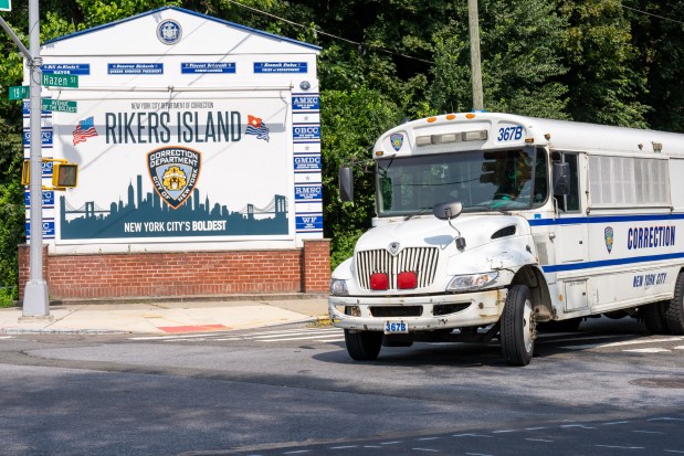 A Department of Correction bus is pictured next to the Rikers Island sign in Queens on Sept. 13, 2021. (Theodore Parisienne for New York Daily News)