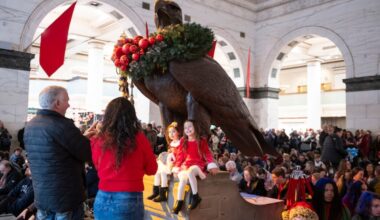 Victoria Santini (left), 4, and Rose Santini (right), 6, sit for a picture with the Wanamaker Eagle inside the Wanamaker Building before the start of the Wanamaker Light Show on Saturday, Nov. 29, 2025. The light show returns this year after the closing of Macy’s, but it is uncertain if the light show will be able to return next year.