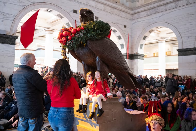 Victoria Santini (left), 4, and Rose Santini (right), 6, sit for a picture with the Wanamaker Eagle inside the Wanamaker Building before the start of the Wanamaker Light Show on Saturday, Nov. 29, 2025. The light show returns this year after the closing of Macy’s, but it is uncertain if the light show will be able to return next year.