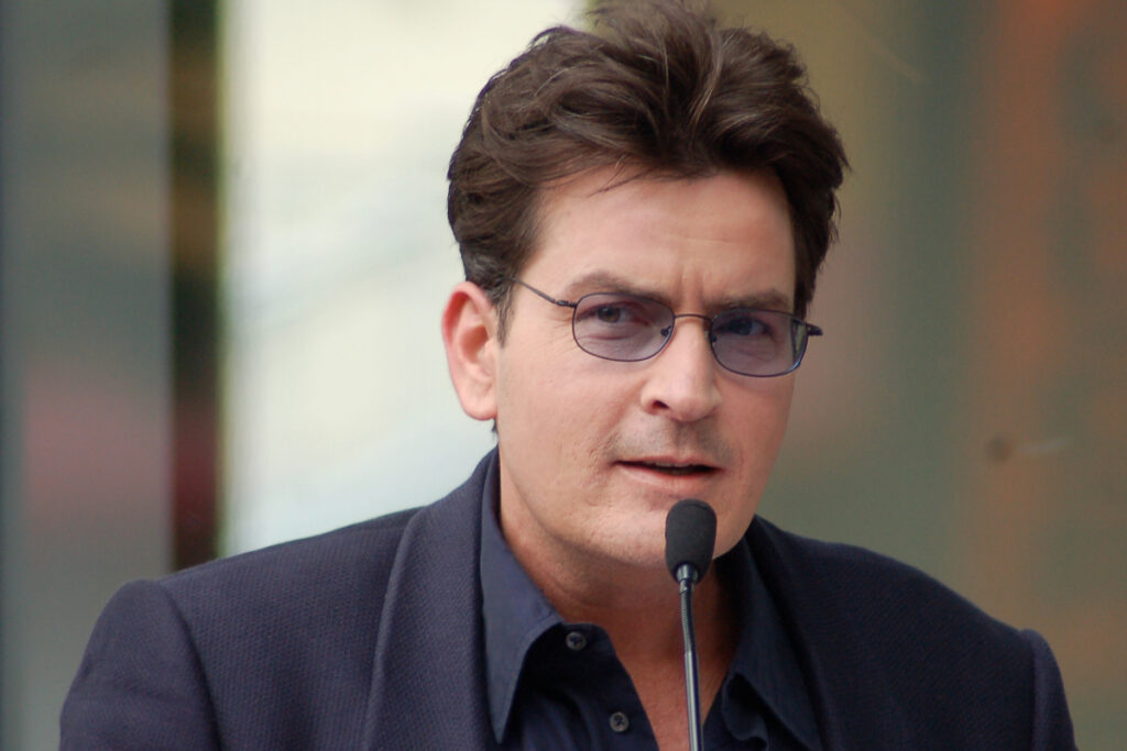Image shows Charlie Sheen talking into a microphone at an event.