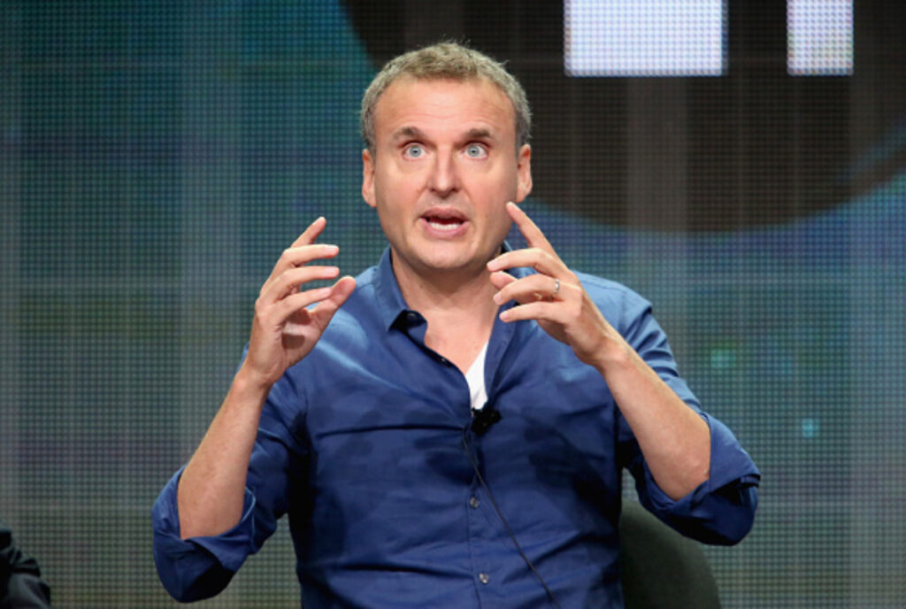 Image shows Phil Rosenthal speaking on stage at an event.