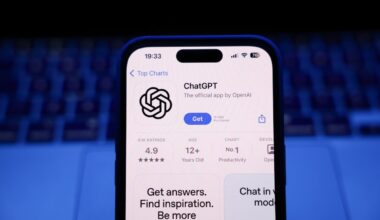 A laptop keyboard and ChatGPT on App Store displayed on a phone screen.
