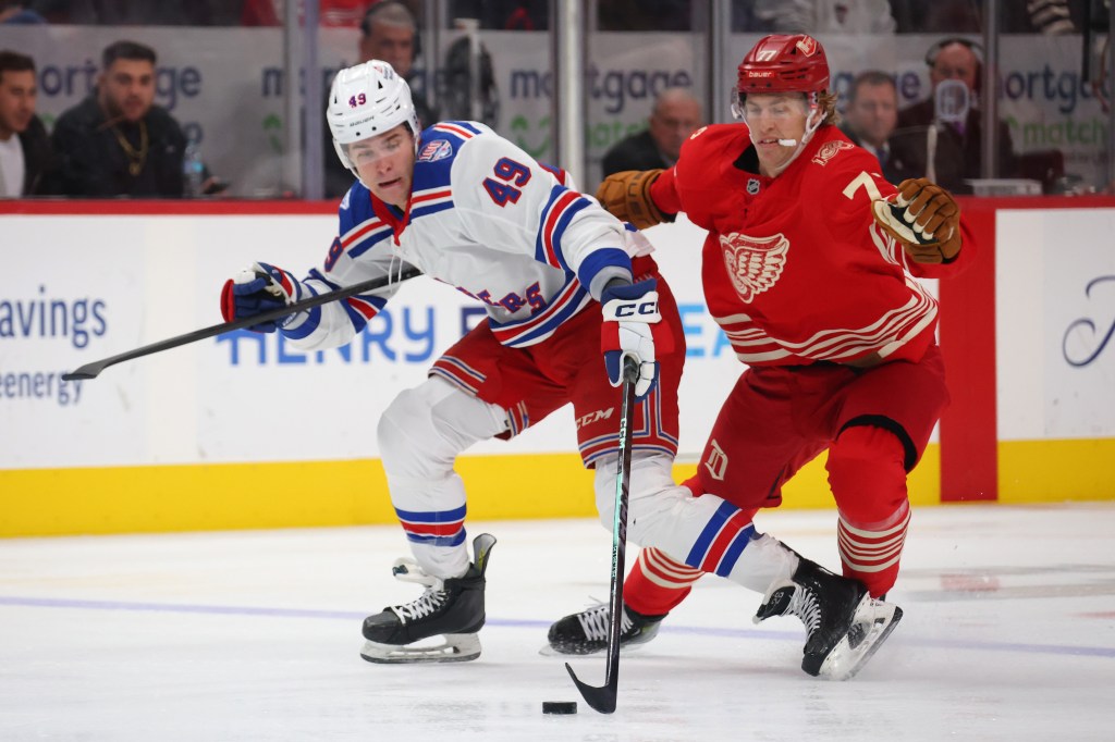 Jaroslav Chmelar #49 of the New York Rangers tries to get around the stick of Simon Edvinsson #77 of the Detroit Red Wings during the third period at Little Caesars Arena on November 07, 2025 in Detroit, Michigan.