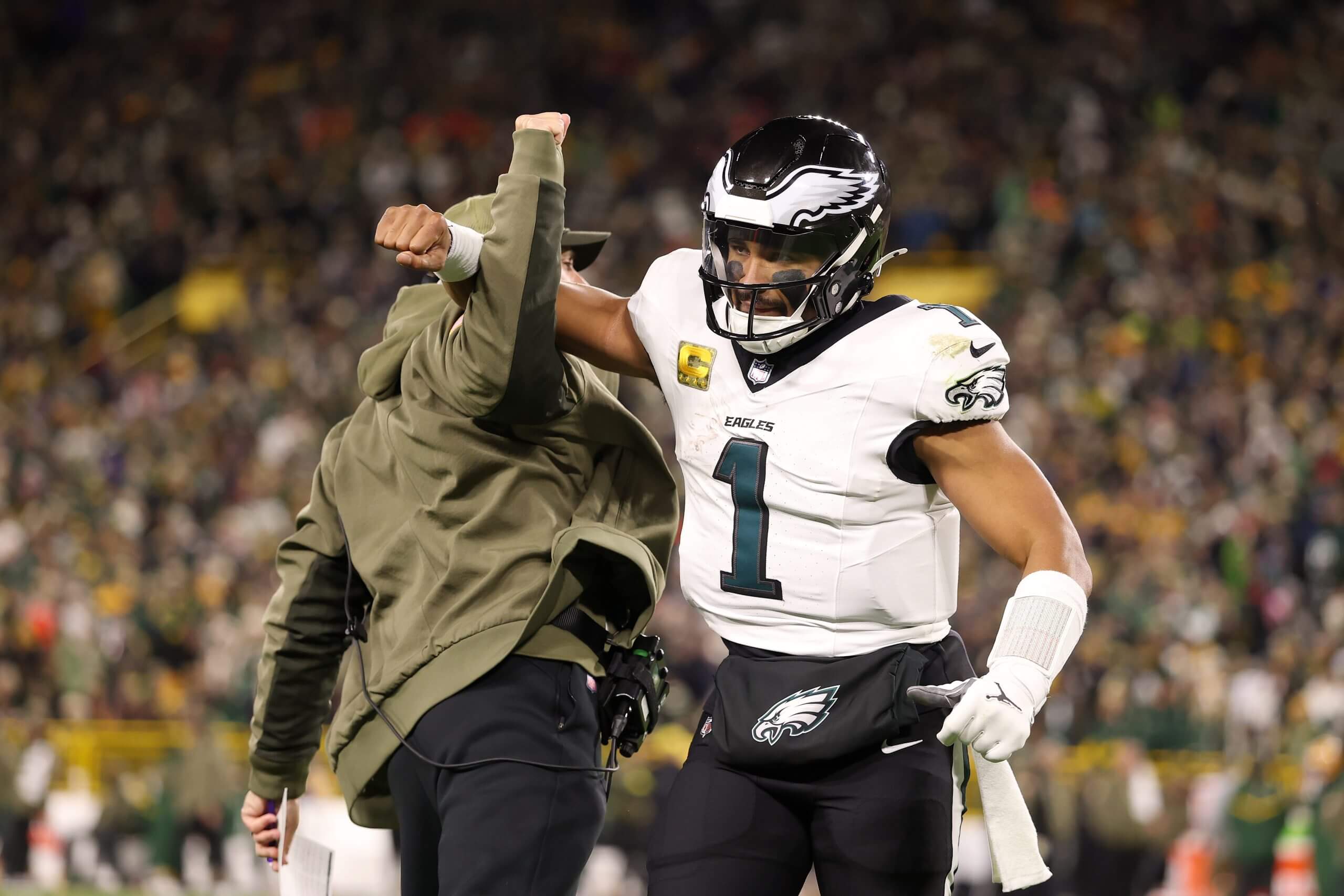 Jalen Hurts, No. 1 of the Philadelphia Eagles, celebrates a touchdown by jumping and locking arms with coach Nick Sirriani.