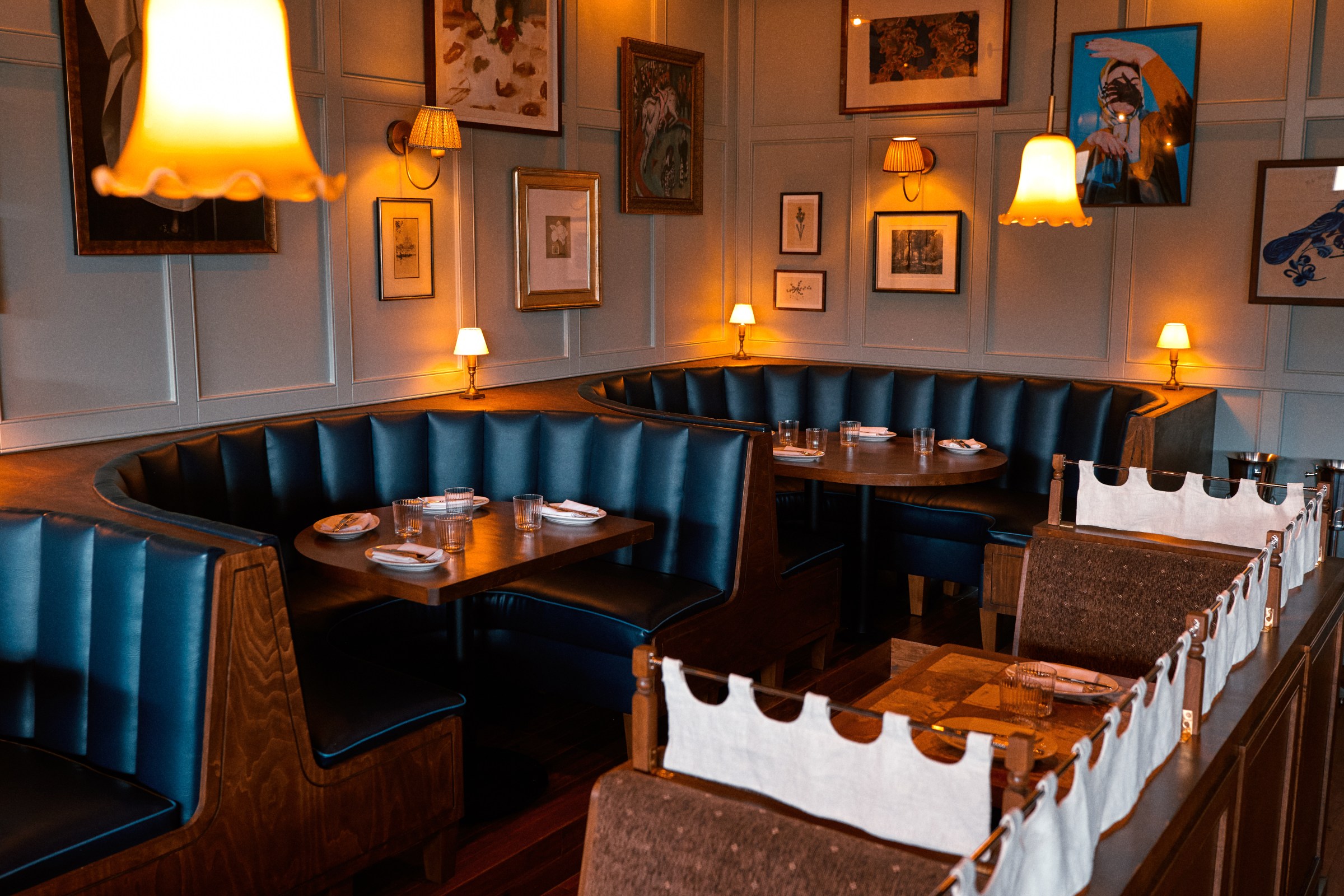 Curved banquette seating with black upholstery and pictures on the walls