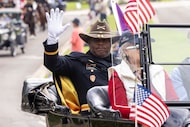 Parade marshal Army Col. (Ret.) Joseph Campbell waves to the crowd while riding in the...