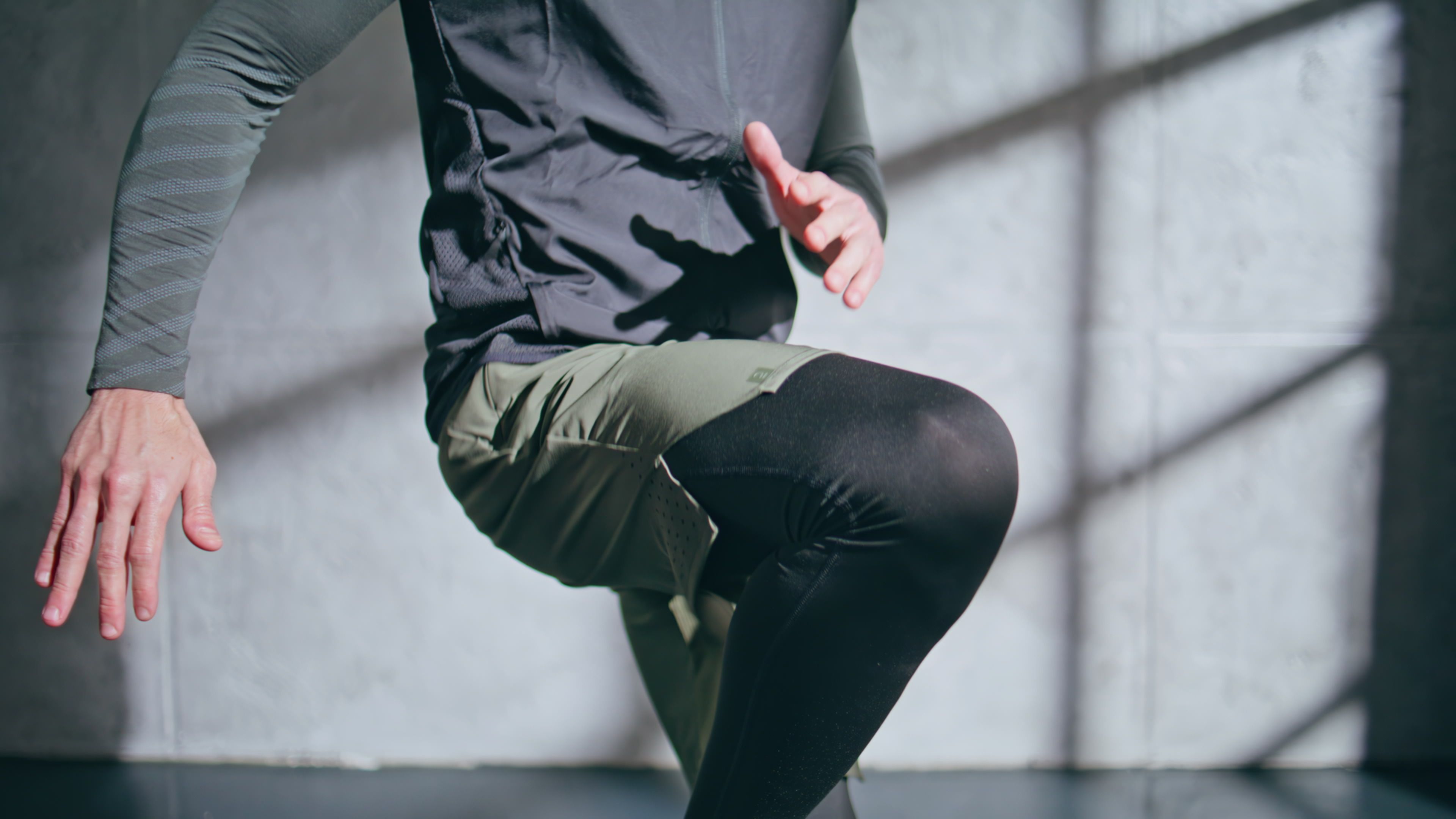 Midsection of man in athletic wear with his right knee lifted and left hand close to his right knee