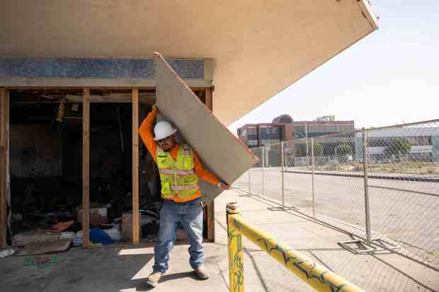 Luis Garcia, of Heritage 1976, works on demolishing a former...