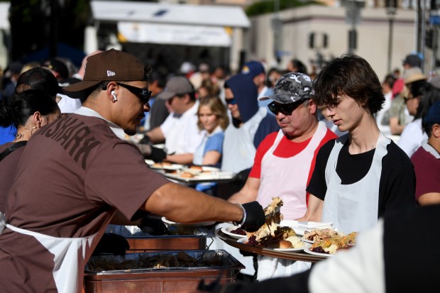Jackson Boyd, right, helps serve food during the annual Los...