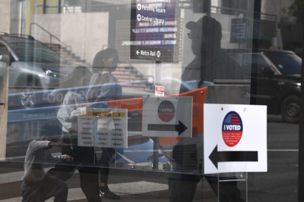Passersby are reflected in the window of the polling place...