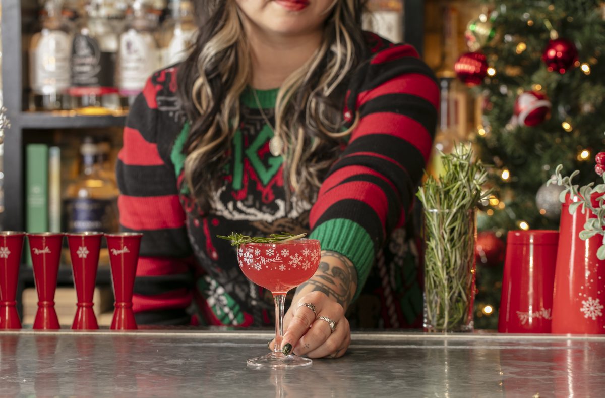 Bartender holding a stemmed glass on a bar top.