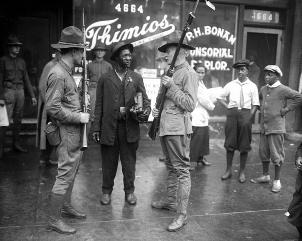 Members of the state militia talk with a man during the...