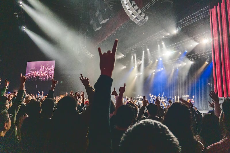 Audience members raise their hands high to be captured in a group photo.