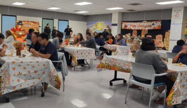 People eating at tables decorated with Thanksgiving tablecloths
