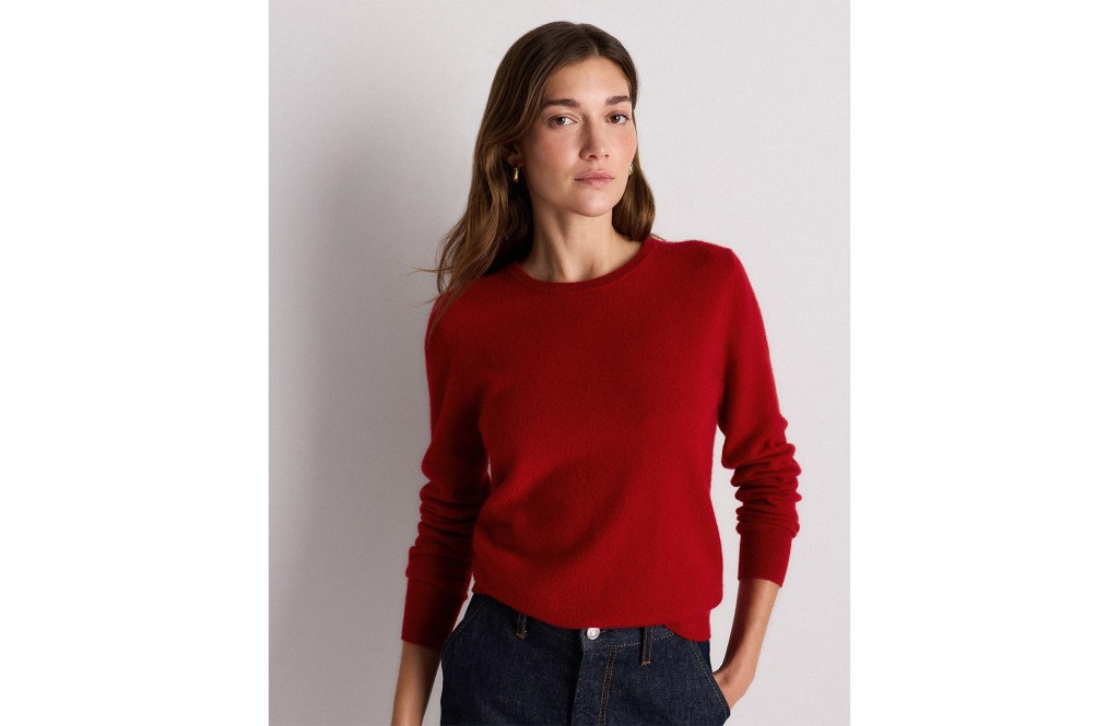 A woman wearing a red sweater and dark jeans.