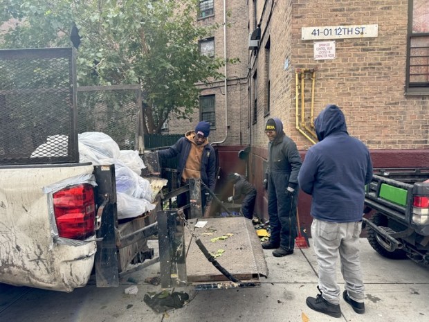 NYCHA workers removed debris from the fatal apartment fire on Saturday. (Rebecca White / New York Daily News)
