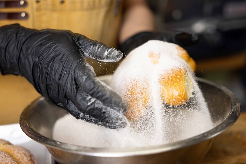 Maria Becerra coats the pan de muerto, the staple bread for Dia de Muertos, with sugar at...