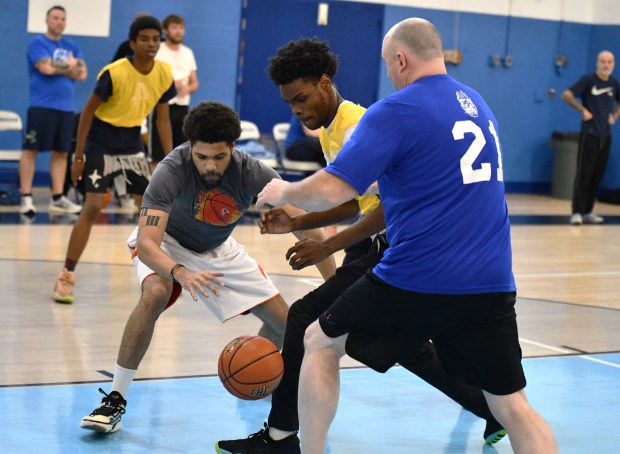 Program volunteer Charles Carlies and Officer Brian Malone grapple with...