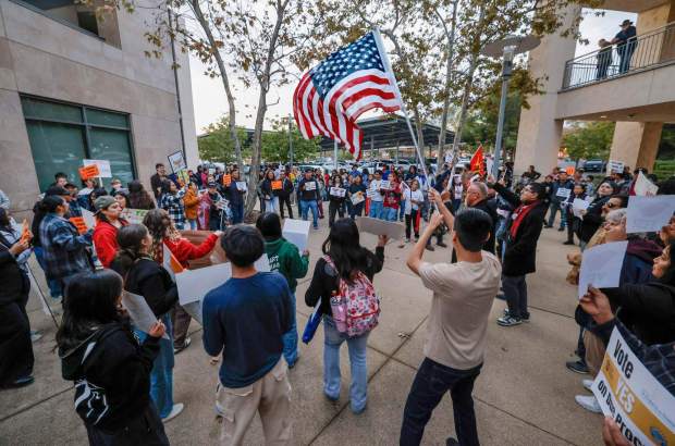 Vista, CA - Before the Vista City Council was to vote on the Community Safety and Due Process Resolution supporters of the resolution have a late afternoon rally at City Hall just prior to the Council meeting and vote. Waving the American flag is Julian Bush. (Charlie Neuman / For The San Diego Union-Tribune)